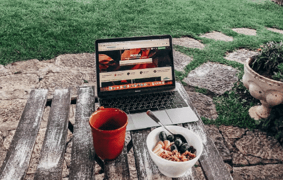 breakfast of healthy cereal and coffee in front of laptop, symbolizing employee wellness measures