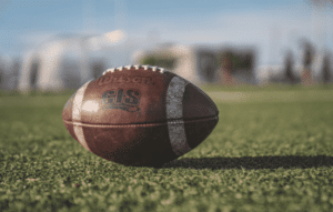 A football sitting on a football field that is empty.