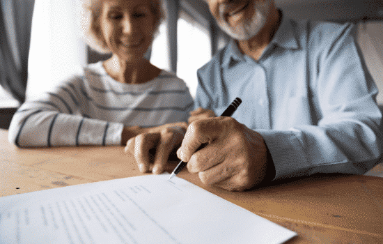 An elderly couple signing a real estate agreement.