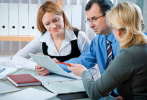 Three employees reviewing paperwork during a meeting.