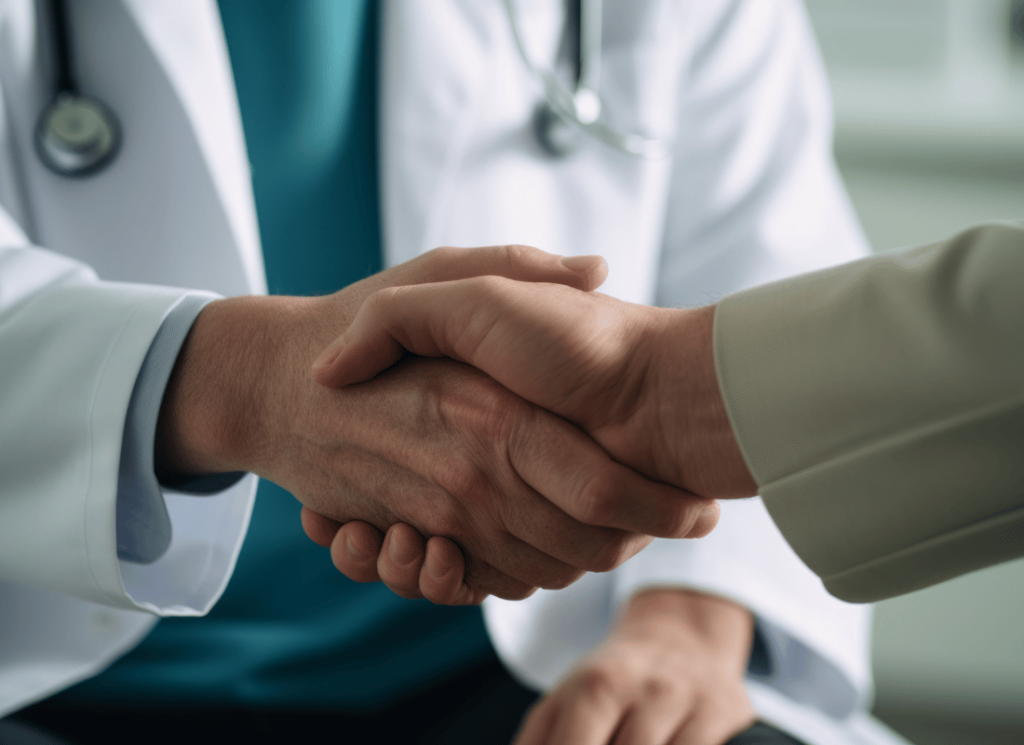 Physician in white coat shakes hand with business associate.