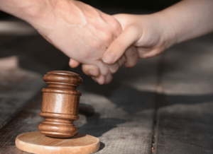 judge's gavel with two hands shaking - this represents the House vs. NCAA settlement