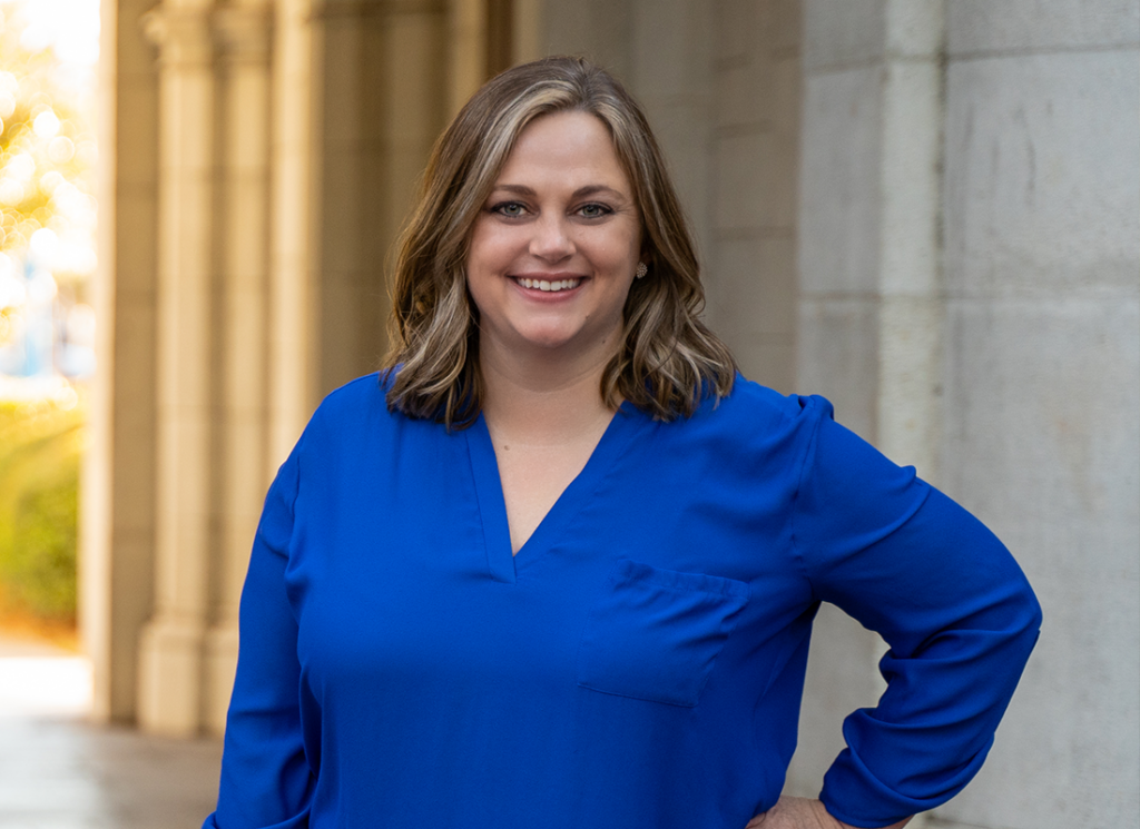 Katie Davis smiling while standing in front of an academic building on the University of Florida campus.