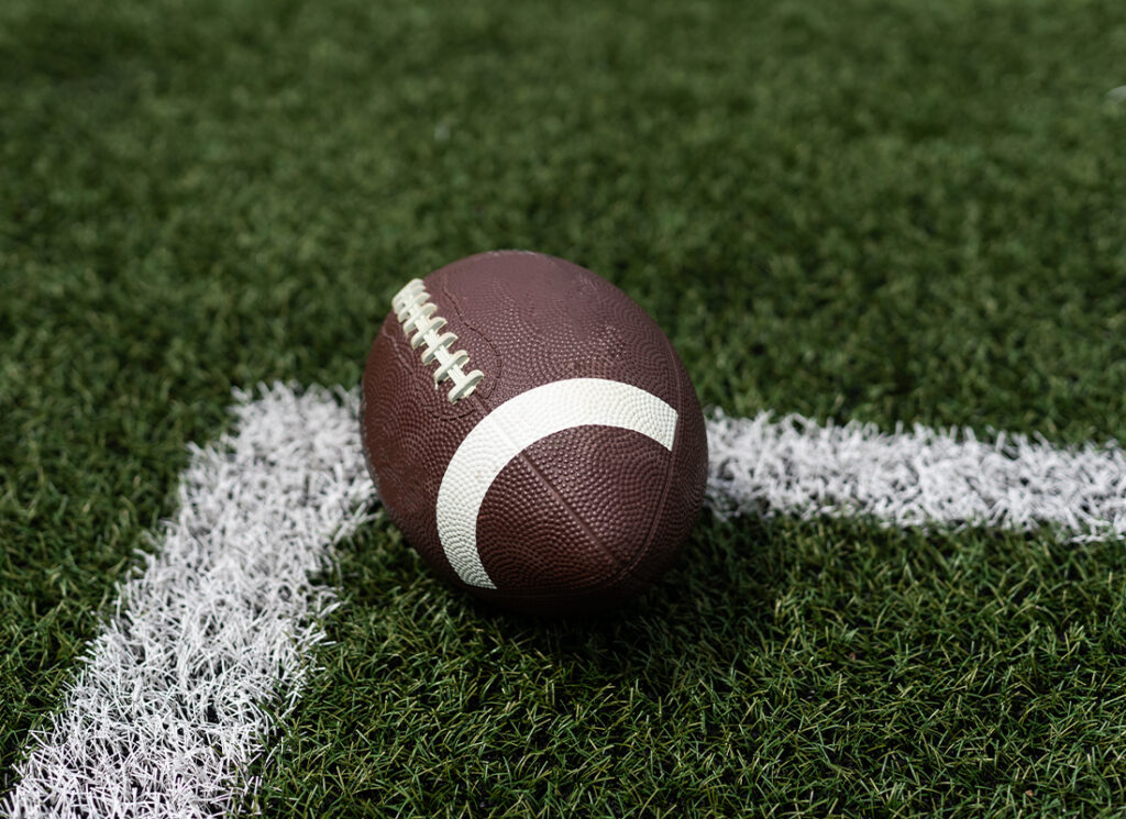 Football stock image with the ball laying on a grass field.