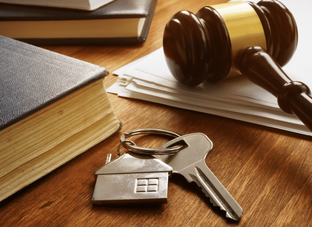 A gavel, a stack of legal documents, a book, and a house-shaped keychain with keys are placed on a desk, symbolizing the legal and financial impact of tax law changes.