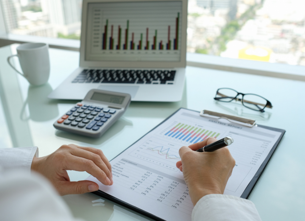 A nonprofit accountant reviews financial documents and charts on a clipboard, with a calculator and laptop, symbolizing audit preparation.