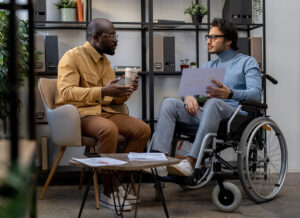 Businessman with drink communicating with his colleague in wheelchair at working meeting in urban office. Master FMLA & ADA: Key Insights for Leave & Accommodations