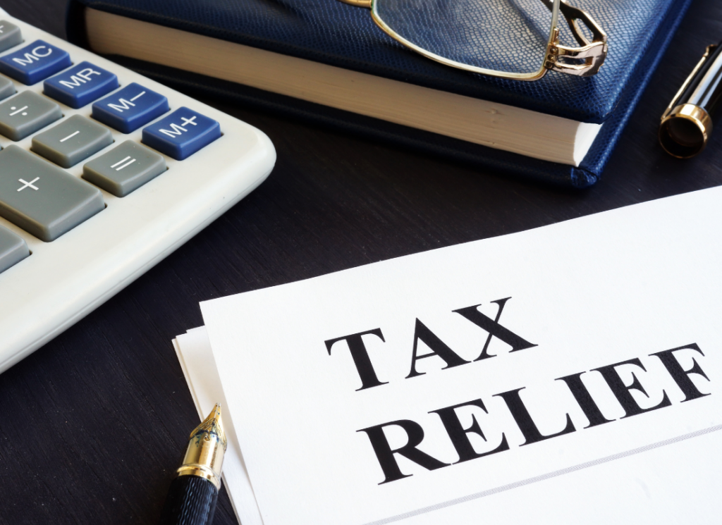 A document labeled 'Tax Relief' is on a desk alongside a calculator, pen, and notebook, symbolizing tax planning for the Federal Disaster Tax Relief Act.