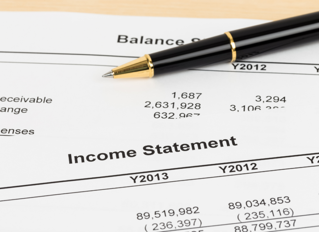 A close-up of an income statement and balance sheet with a black and gold pen, representing real estate fund financial statements.