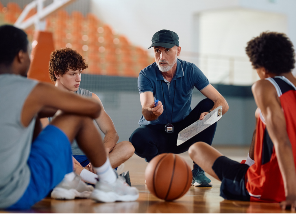 A basketball coach discussing strategy and addressing his team on a court, representing themes of accountability for college athletes.