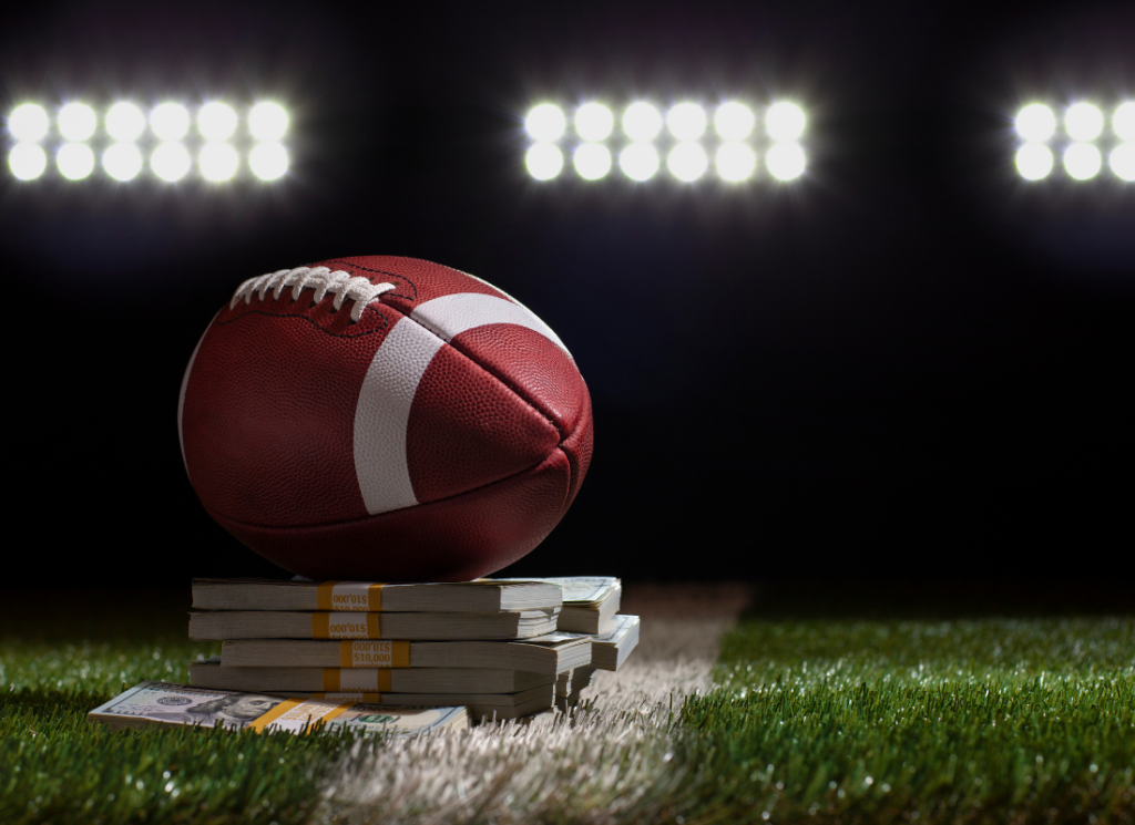 A football resting on a stack of money under bright stadium lights, symbolizing the financial and legal implications of revenue-sharing in college sports.