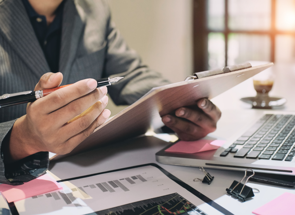 A business professional reviews financial documents and charts on a clipboard, analyzing real estate investment tax strategies.