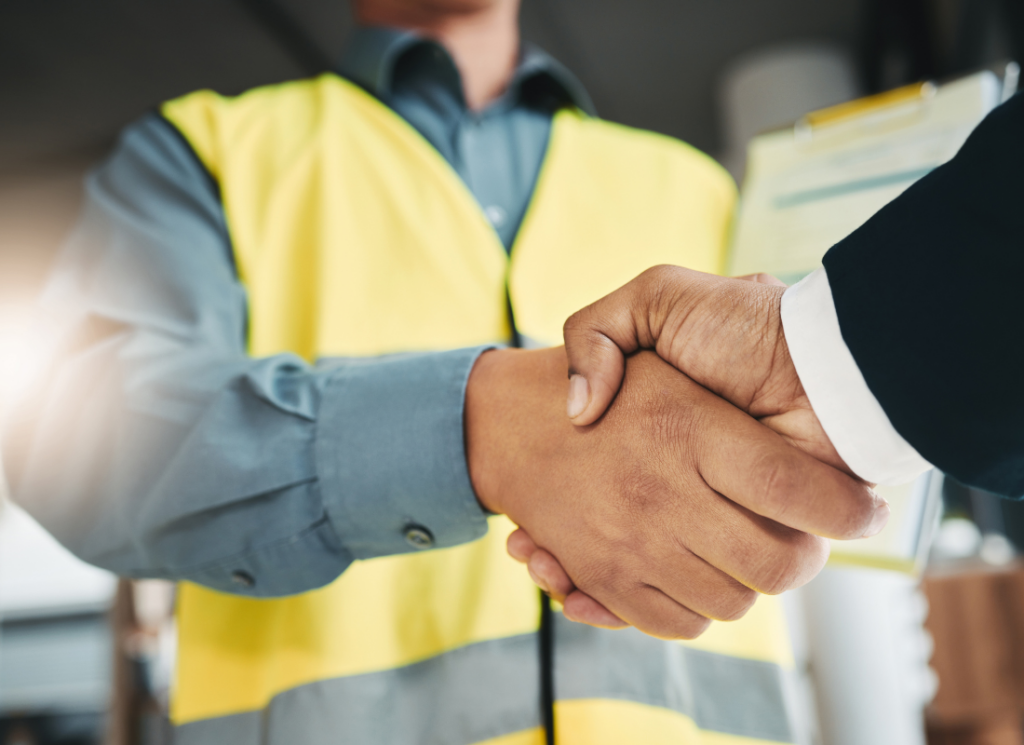 A construction professional in a yellow safety vest shakes hands with a businessperson, symbolizing private equity investment in the construction industry.